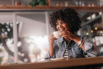 Fototapeta na wymiar Smiling young female having coffee in a restaurant