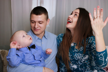 mom and dad playing with their baby son. Funny baby with father and mother playing