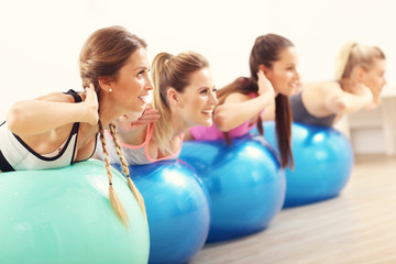 Group of smiling people doing aerobics with balls