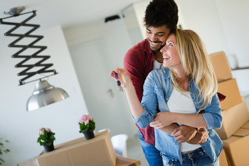 Young married couple with boxes and holding flat keys