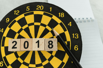 New year planning target concept with wooden blocks number 2018 on dart board, pencil and note paper