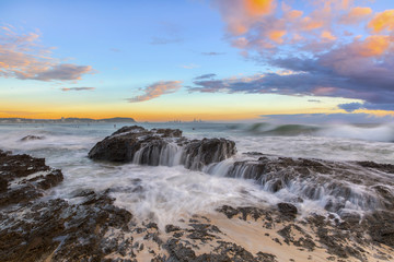 Ocean tide cascading over the rocks during sunrise at Currumbin Rock, Gold Coast