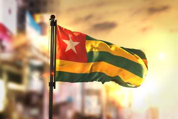 Togo Flag Against City Blurred Background At Sunrise Backlight