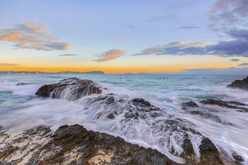 Fototapeta na wymiar Ocean tide cascading over the rocks during sunrise at Currumbin Rock, Gold Coast