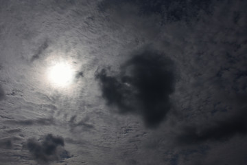 タイトル : 厚い雲から透ける太陽光と黒い雲「空想・太陽を見つめる黒いモンスター（ゴールデンレトリバー、セントバーナードなどの大型犬の顔のイメージ）」介助、見つめる、 見守る、やさしい眼差し、動物愛護、介護などのイメージ。周囲に文字スペース（案「介助犬と生きる明るい未来」）