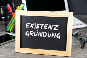 Ein Büro und eine Kreidetafel mit dem Wort Existenzgründung