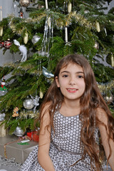 Mädchen lächelt vor dem Weihnachtsbaum