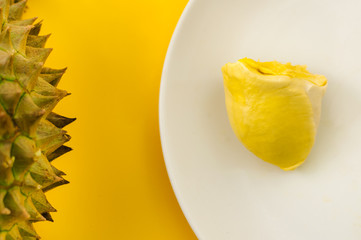 Durian on a white plate with green spike rind  and yellow background, king of the fruit but smelly in Thailand and south east asia; soft  focus
