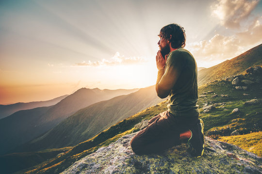 Man praying at sunset mountains Travel Lifestyle spiritual relaxation emotional concept vacations outdoor harmony with nature landscape