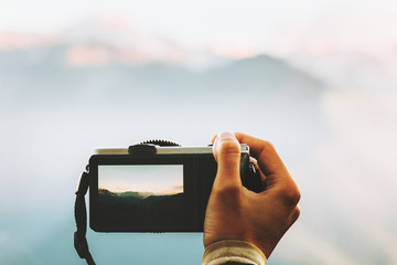 Hand with photo camera taking shot of mountains landscape outdoor Travel Lifestyle adventure summer vacations