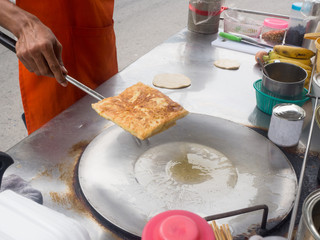 man taking roti from pan, yellow indian food