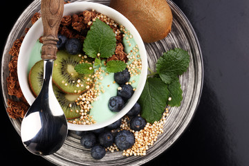 Smoothies bowl - matcha green tea breakfast superfoods topped with chia, pumpkin seeds, bee pollen, granola, kiwi and blueberries.