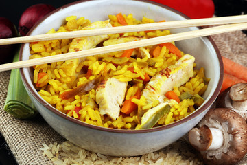 Homemade Chinese fried rice with vegetables, chicken and fried eggs served on a plate with chopsticks