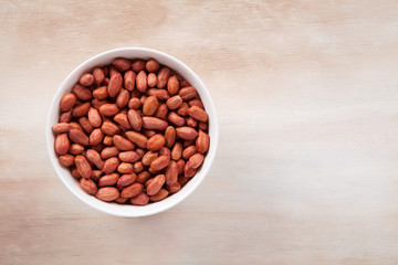 Peanuts in a bowl on a wooden background.