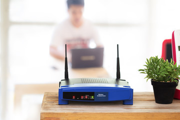 closeup of a wireless router and a young man using Laptop and notebook computers on living room at...