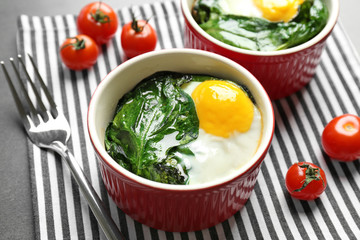 Portions of eggs Florentine with cherry tomatoes on striped napkin