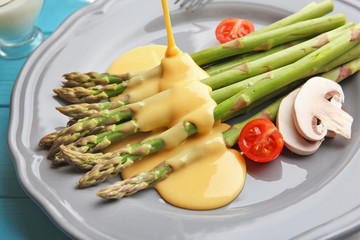 Pouring cheese sauce onto asparagus, close up