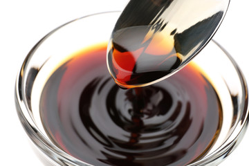 Bowl with tasty soy sauce and spoon, closeup