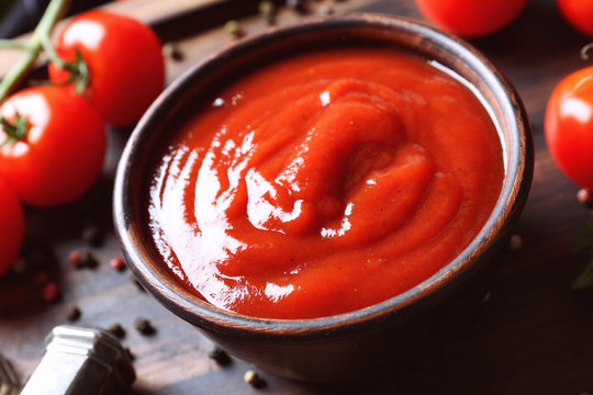 Delicious ketchup in bowl with ingredients on tray, closeup