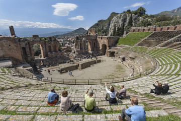 Tourists admiring beautiful view from the theater to volcano Etna, Taormina, Italy