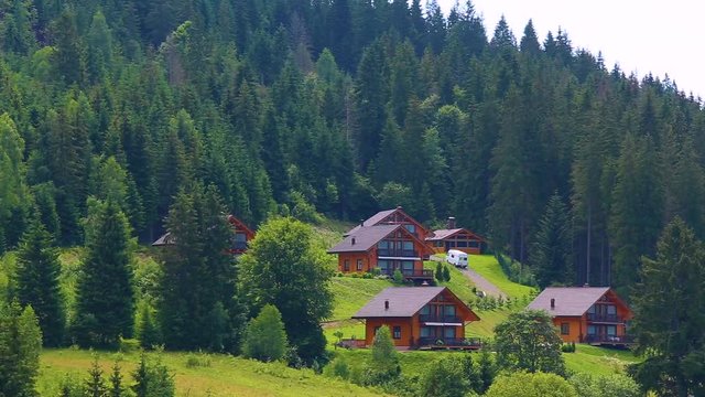 Many cozy wooden houses in beautiful scenic place for rest over scenic green mountain landscape. Ukraine area. Camera moving from left to right. Real time full hd video footage.