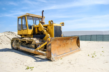 crawler caterpillar bulldozer used to push sand  on beach - obrazy, fototapety, plakaty