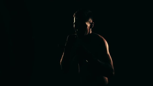 Boxer training in a gym, dramatic lighting. Slow motion