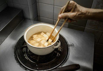 Cooking deep fried fish tofu in dim light kitchen