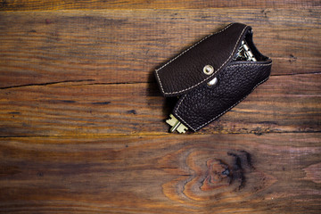 Leather key case with keys on the wood background. Dark background. Keychain. Key case in the form...