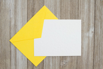 An embossed blank white card with yellow envelope on weathered wood