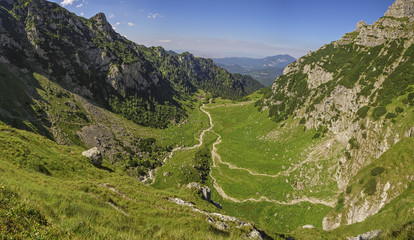 Fototapeta na wymiar Alpine landscape with the vast green Malaiesti Valley in Bucegi mountains, Romania. Romanian travel destinations, touristic attractions.