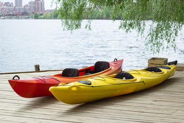 Two kayaking boats on wooden deck at station near lake