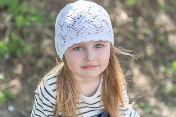 Cute little girl smiling shyly, standing outside