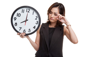 Sleepy young Asian woman with a clock in the morning.
