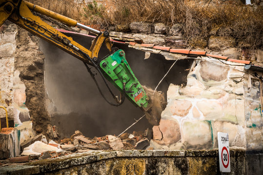 Excavadora tirando una casa en un lugar publico
