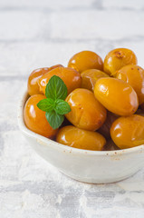 Raw fresh dates and green mint in a bowl on brick wall background close up. Selective focus.