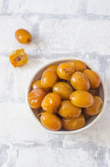 Raw fresh dates in a bowl on brick wall background close up. Selective focus.