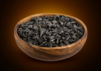Black Sunflower seeds in wooden bowl isolated