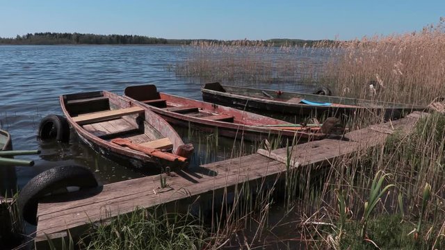 Old wooden fishing boats floating near the lake footbridge