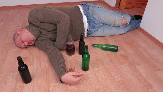 Drunk man sleeping on floor after alcohol abuse