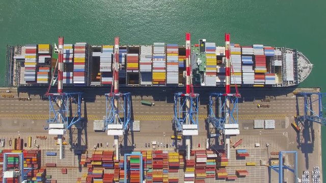 Commercial port with container ship during loading and unloading - Top down view.