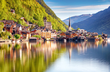 Fototapeta na wymiar Classic postcard view of famous Hallstatt lakeside town reflecting in Hallstattersee lake in the Austrian Alps in scenic morning light on a beautiful sunny day in summer, Salzkammergut region, Austria