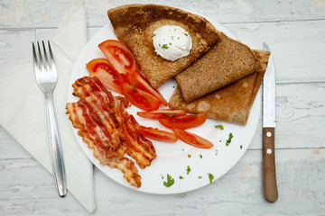 Top view on breakfast with pancakes, bacon and tomato