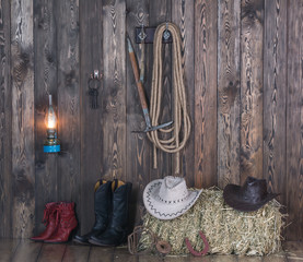 A cowboy hat, boots on the background of an old barn.