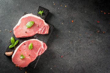 Raw organic meat. Pork steaks, fillets for grilling, baking or frying. On a wooden cutting board,...