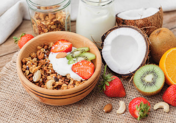Granola with Greek yoghurt and fruit on a wooden background in a rustic style