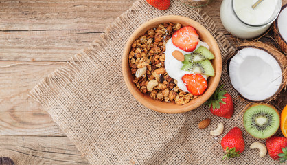 Granola with Greek yoghurt and fruit on a wooden background in a rustic style