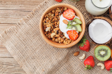 Granola with Greek yoghurt and fruit on a wooden background in a rustic style