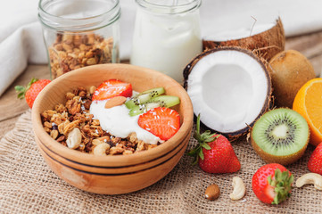 Granola with Greek yoghurt and fruit on a wooden background in a rustic style