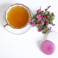 cup of tea with pink apple blossoms and macaroni biscuits